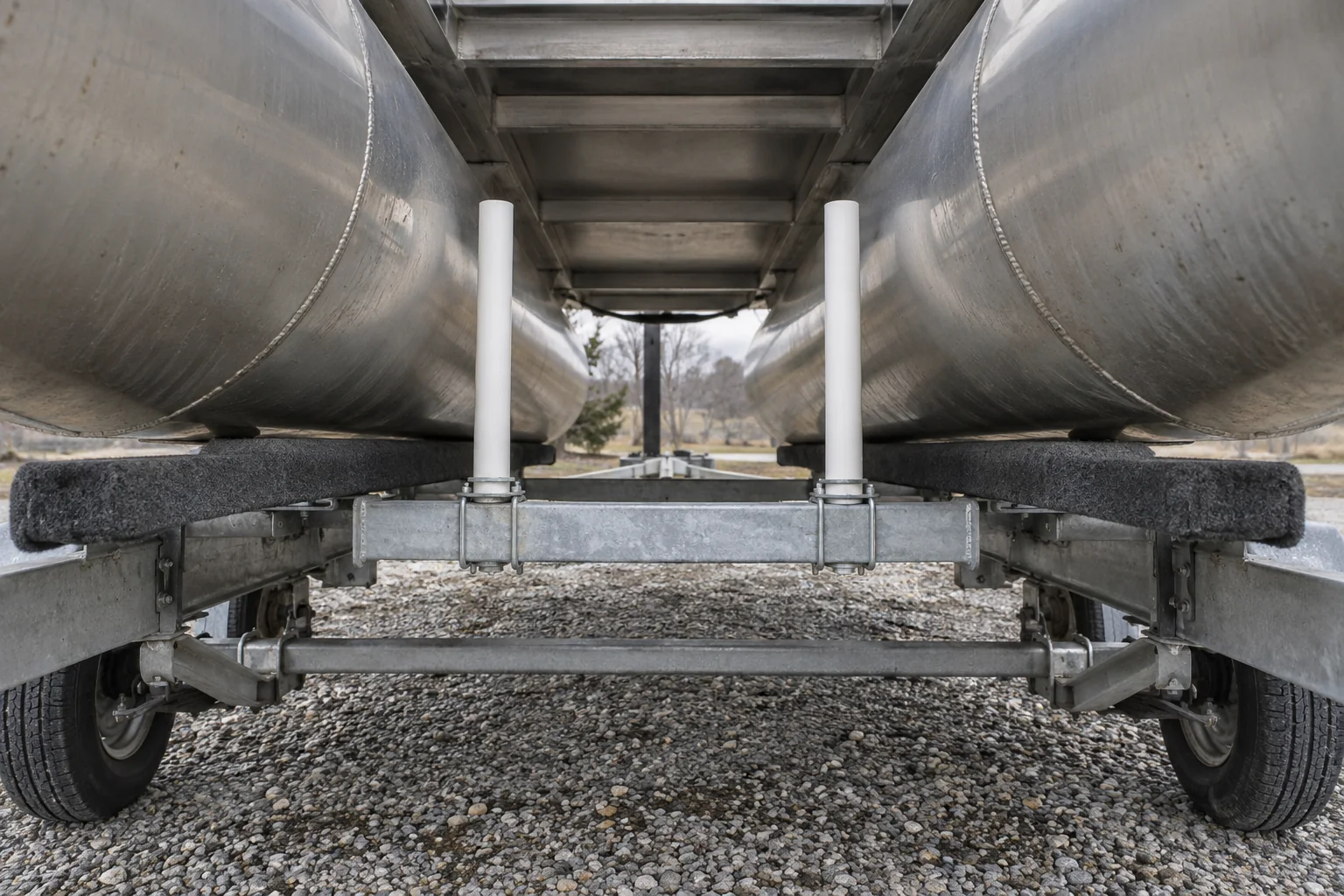 Short white guideposts between two aluminum pontoon tubes above a trailer crossmember