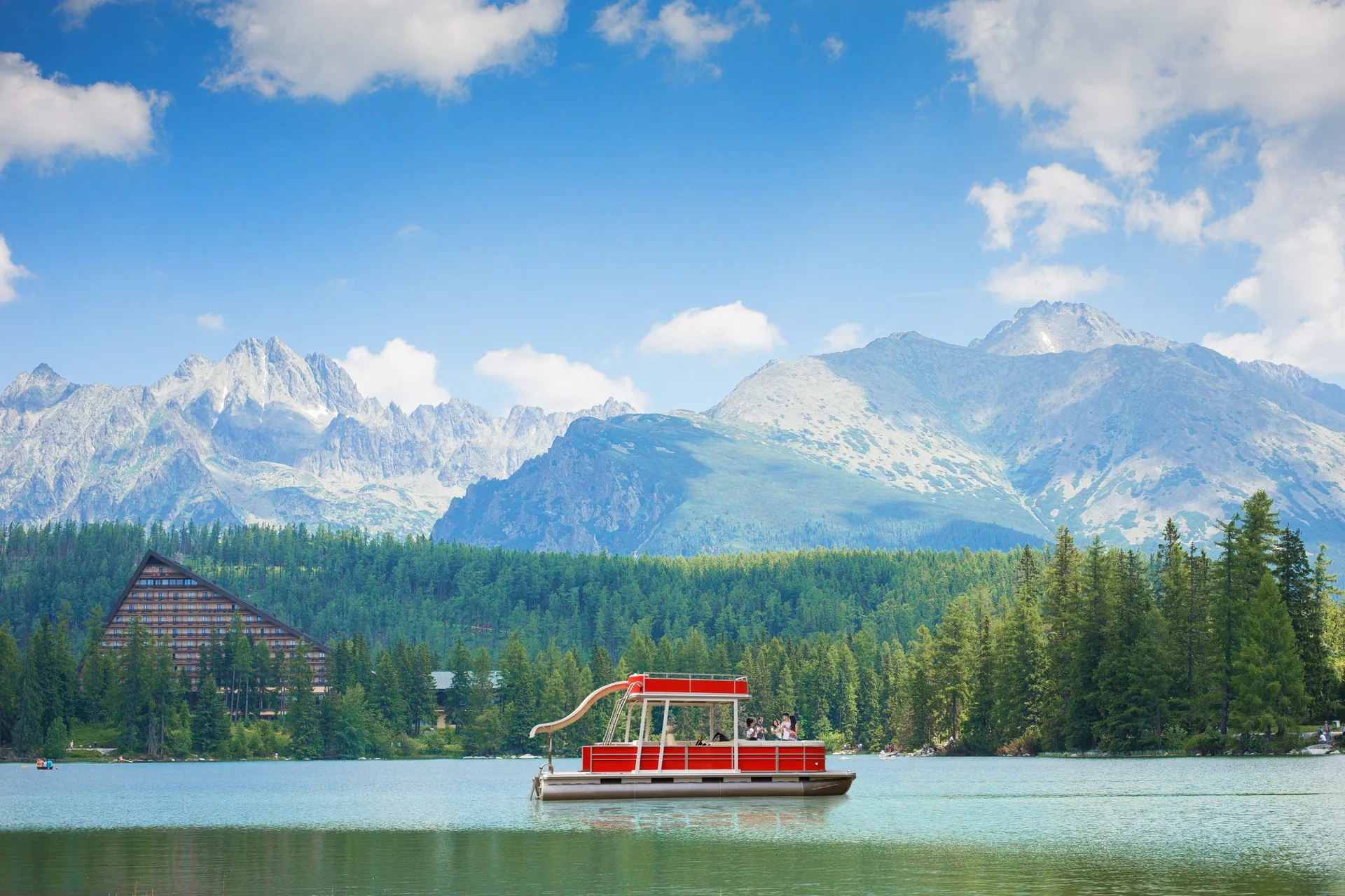 Pontoon boat on a lake surrounded by mountains and forest