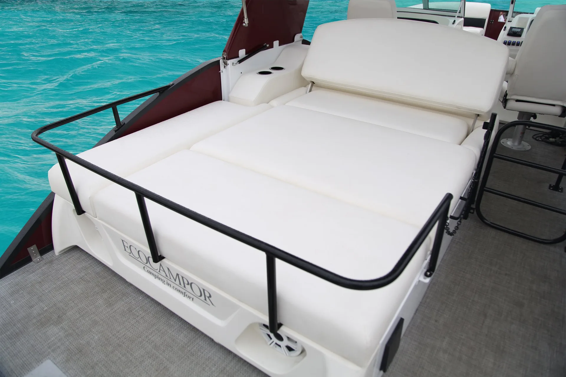 Aft sun pad on a pontoon boat with a rail and ladder behind it