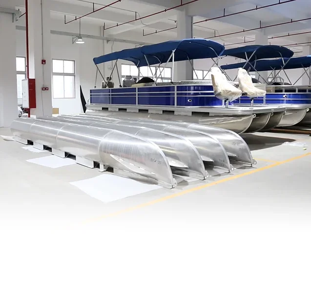 Unassembled pontoon tubes beside fitted pontoon boats in the source workshop